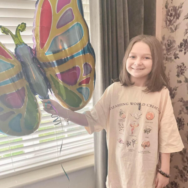 Isla stands with her balloon